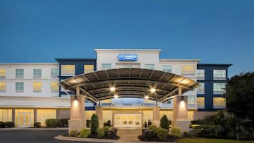 A hotel entrance with a covered walkway, multiple floors, and a clear sky.