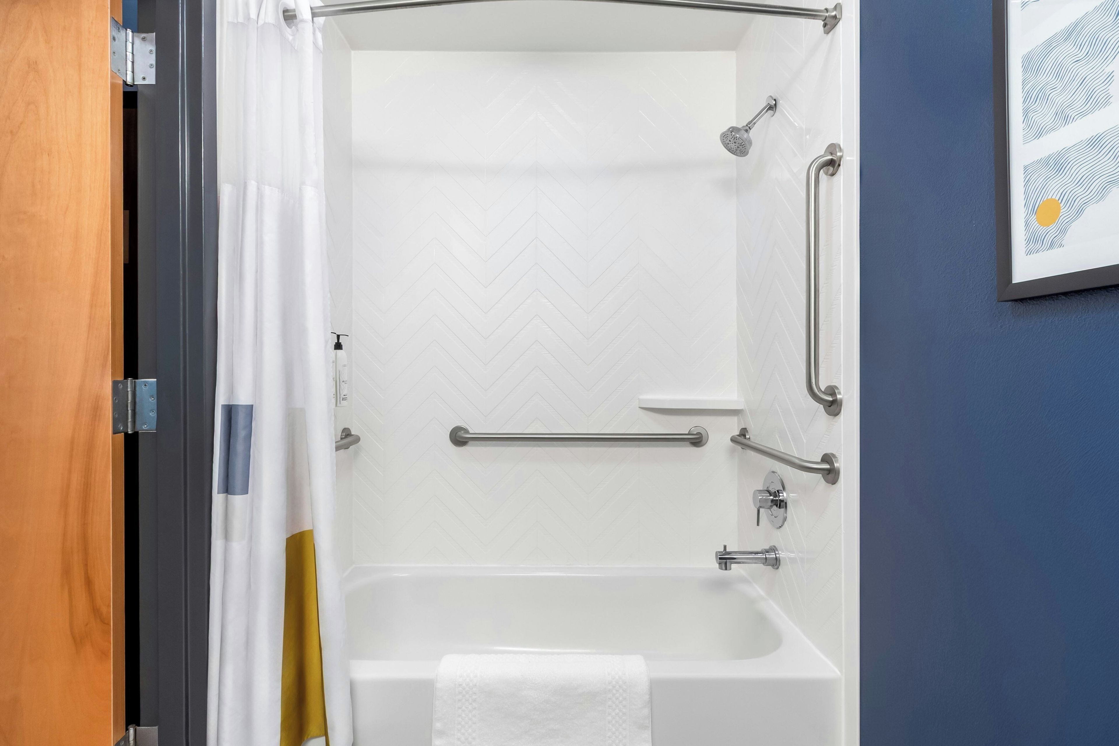 Ducha con cabezal de ducha de mano, barras de apoyo y un perchero.