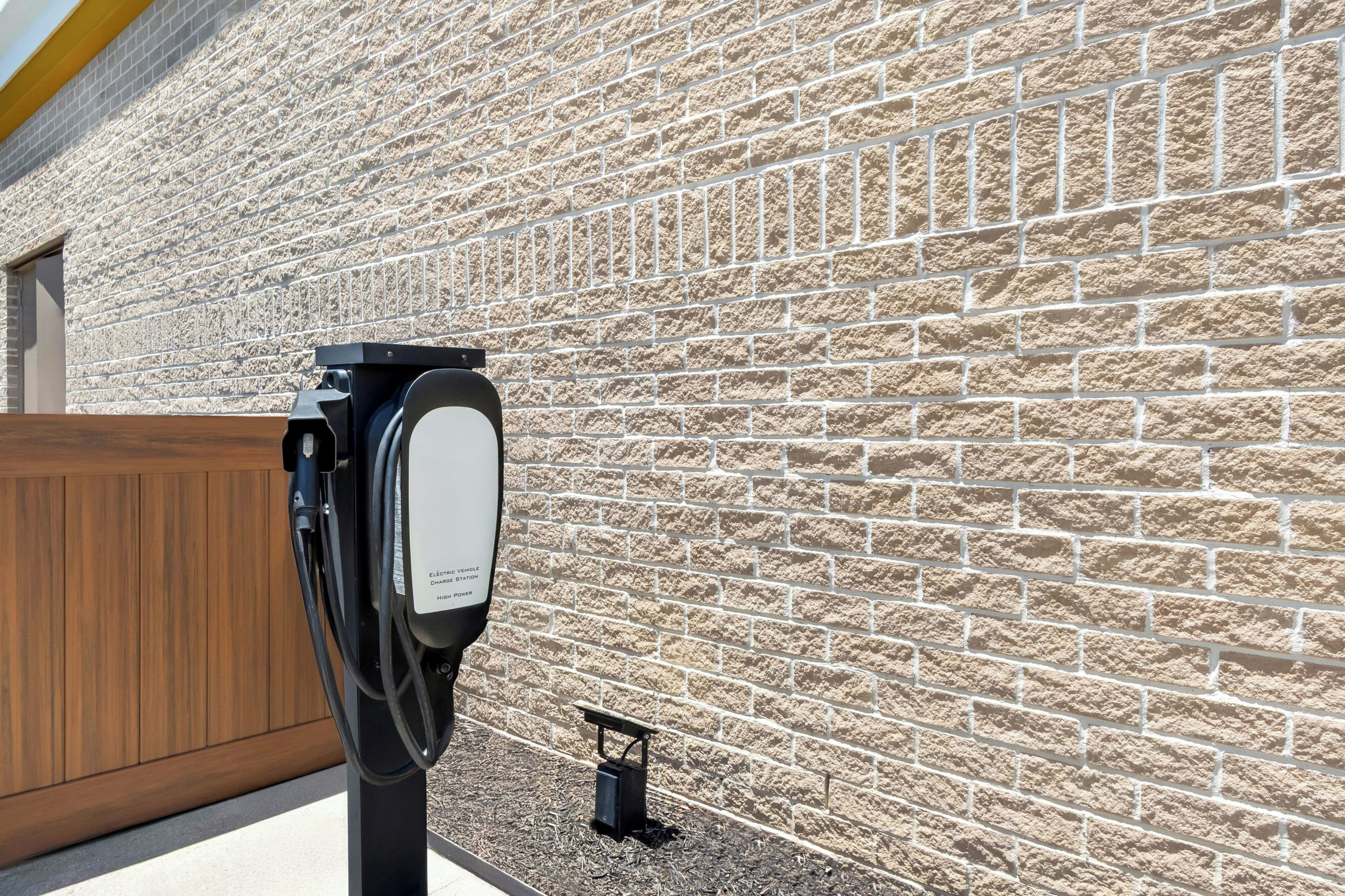 An electric vehicle charging station with a brick wall in the background.