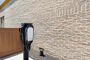 An electric vehicle charging station with a brick wall in the background. - City Express by Marriott Pooler Savannah Airport (Pooler)
