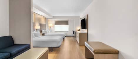 A hotel room with a bed, a sofa, a desk, a TV, and a window.