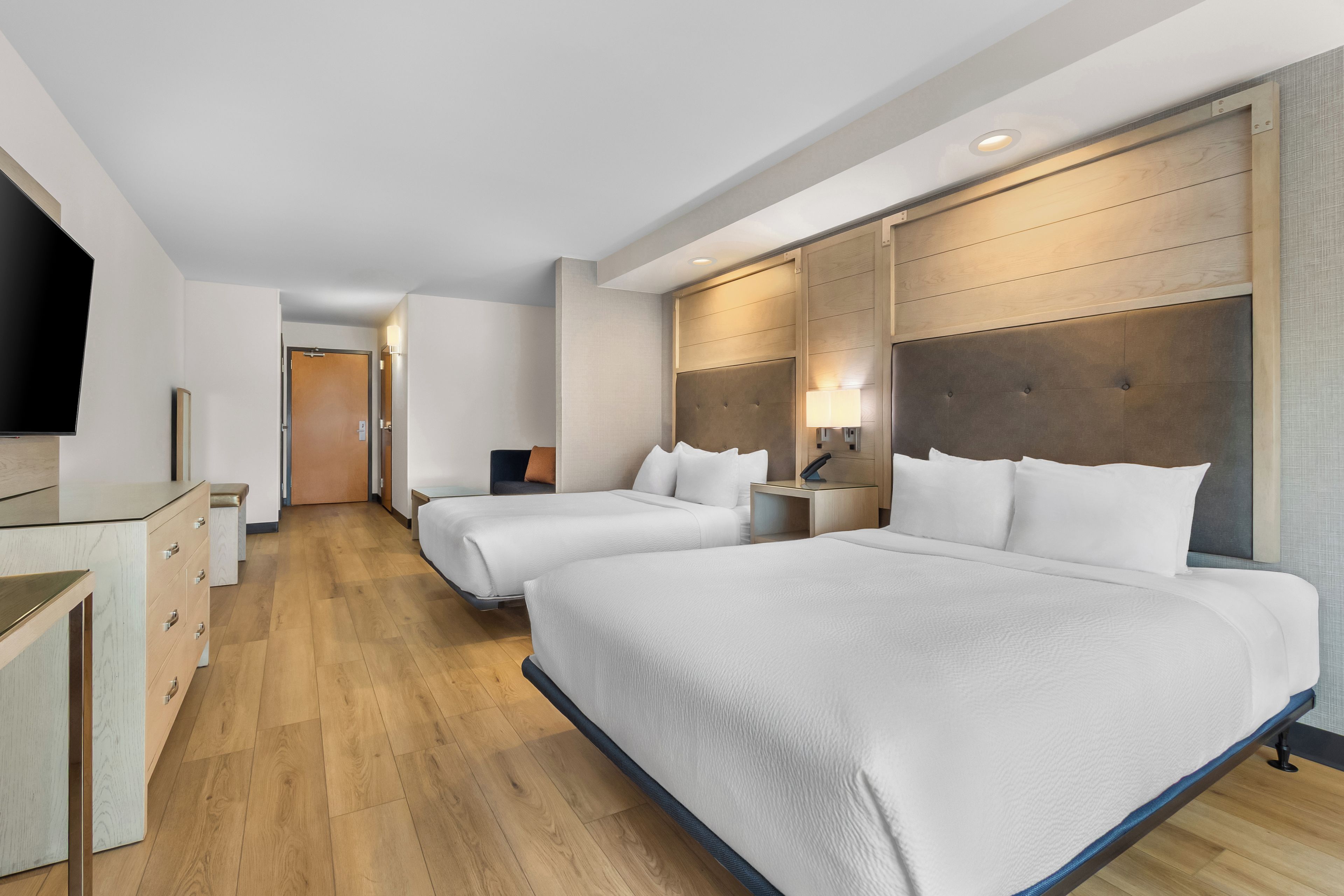 Habitación de hotel con dos camas, un escritorio, un televisor y un armario.
