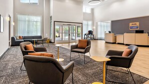 A hotel lobby with a reception desk, seating area with sofas and armchairs, and large windows allowing natural light. - City Express by Marriott Pooler Savannah Airport (Pooler)
