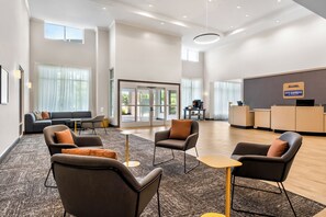 A hotel lobby with a reception desk, seating area with sofas and armchairs, and large windows allowing natural light. - City Express by Marriott Pooler Savannah Airport (Pooler)