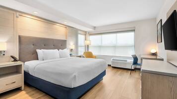 A modern hotel room with a large bed, bedside tables, a desk, and a chair.