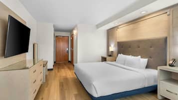 Habitación de hotel con una cama grande, mesitas de noche, un televisor de pantalla plana y un cabecero de madera.