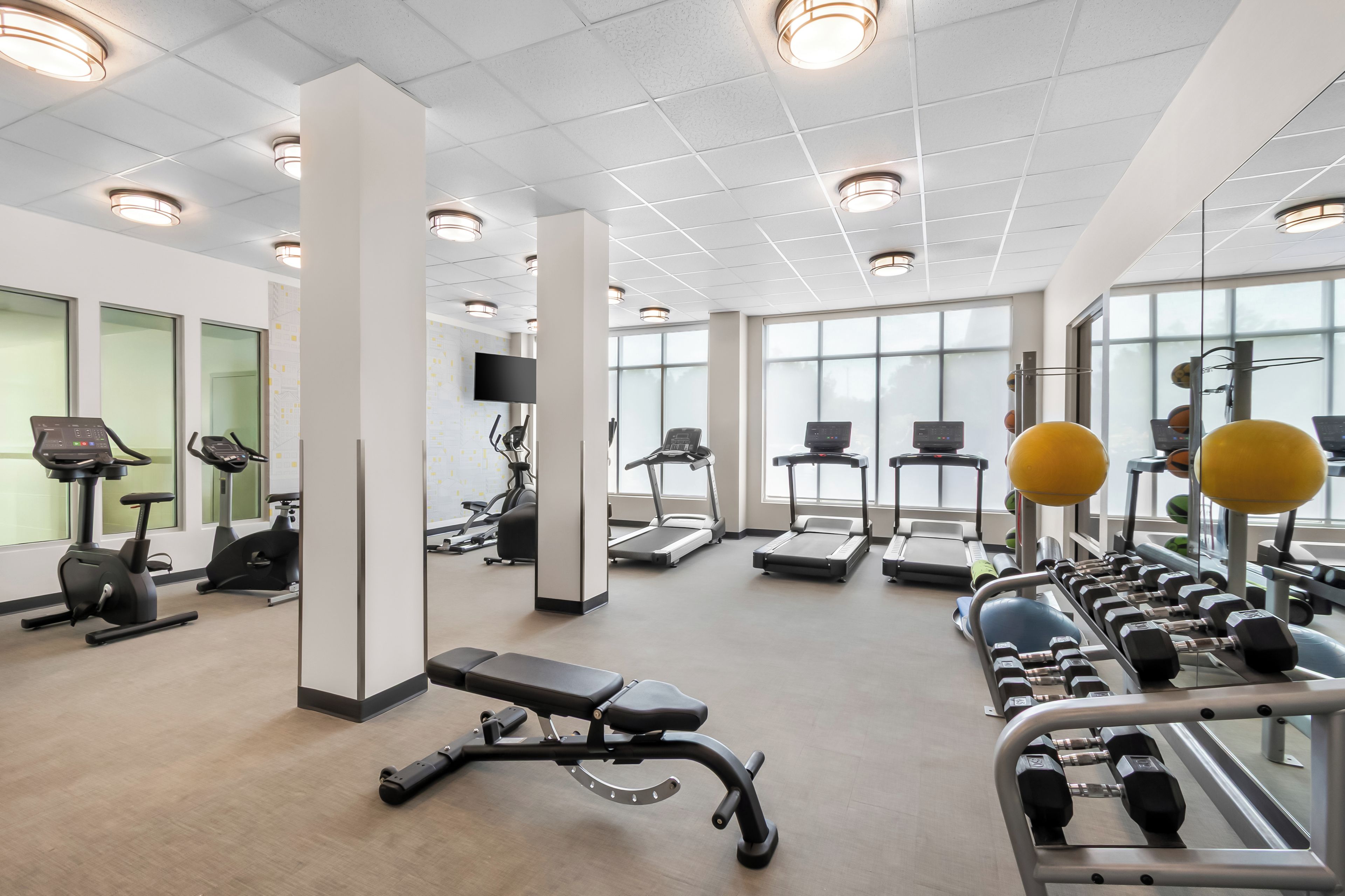 A gym with exercise equipment, large windows, and a clean, modern design.
