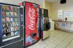 A vending machine with snacks and a Coca-Cola machine. There is a sign for guest laundry and a refrigerator. - Holiday Inn Express Hotel & Suites San Angelo by IHG (San Angelo)
