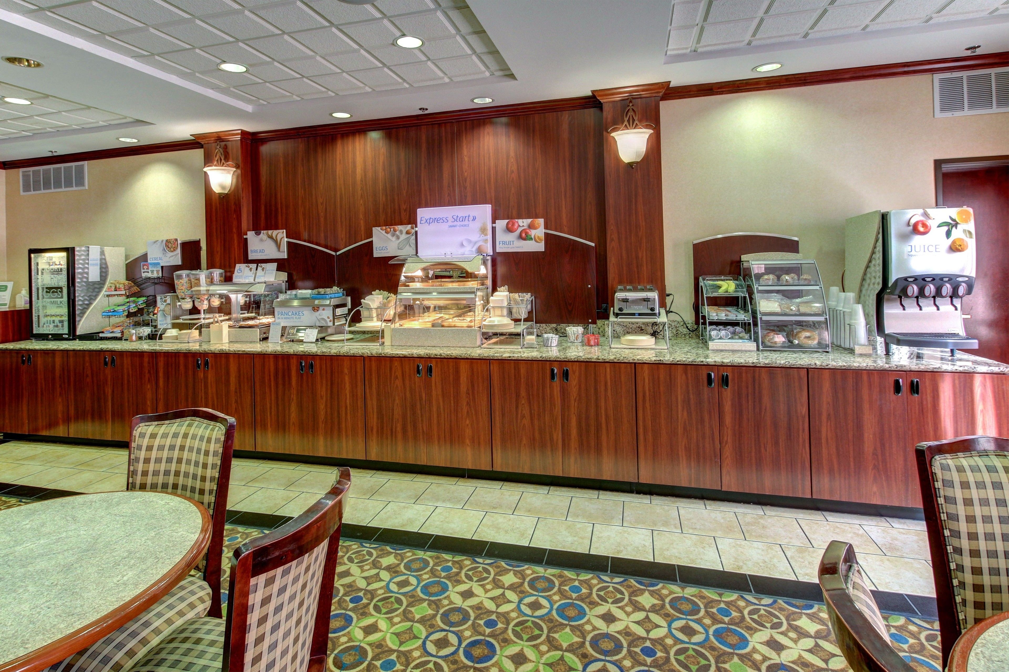 A hotel lobby with a reception desk, seating area, and a juice dispenser.