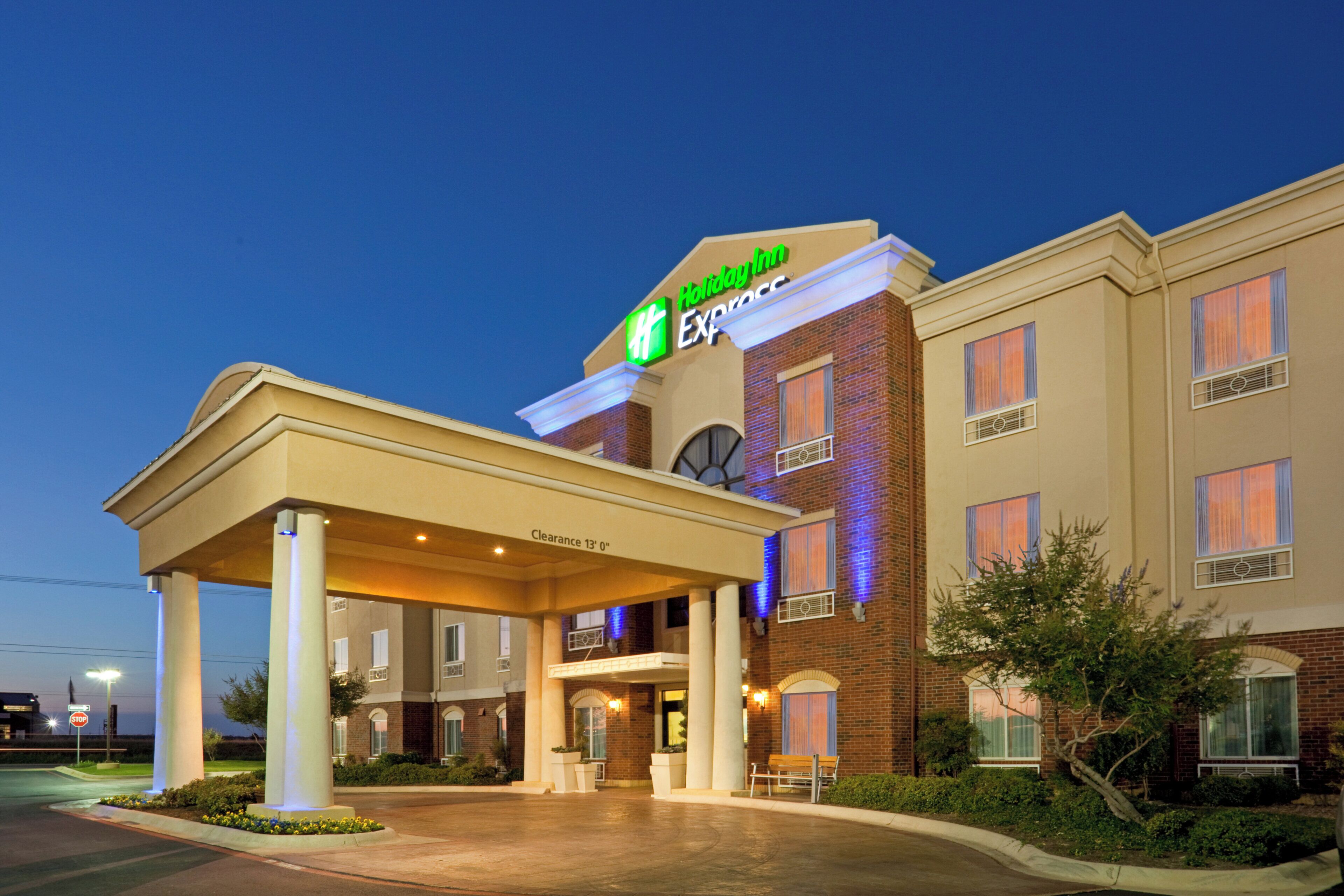 A Holiday Inn Express hotel with a covered entrance, a clock, and a clear sky.