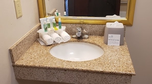 A bathroom sink with toiletries, a mirror, and a tissue box. - Holiday Inn Express Hotel & Suites San Angelo by IHG (San Angelo)