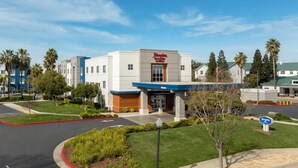 A Hampton Inn & Suites by Hilton hotel with a modern facade, a landscaped entrance, and a parking area. - Hampton Inn & Suites Sacramento-Airport-Natomas (Sacramento)