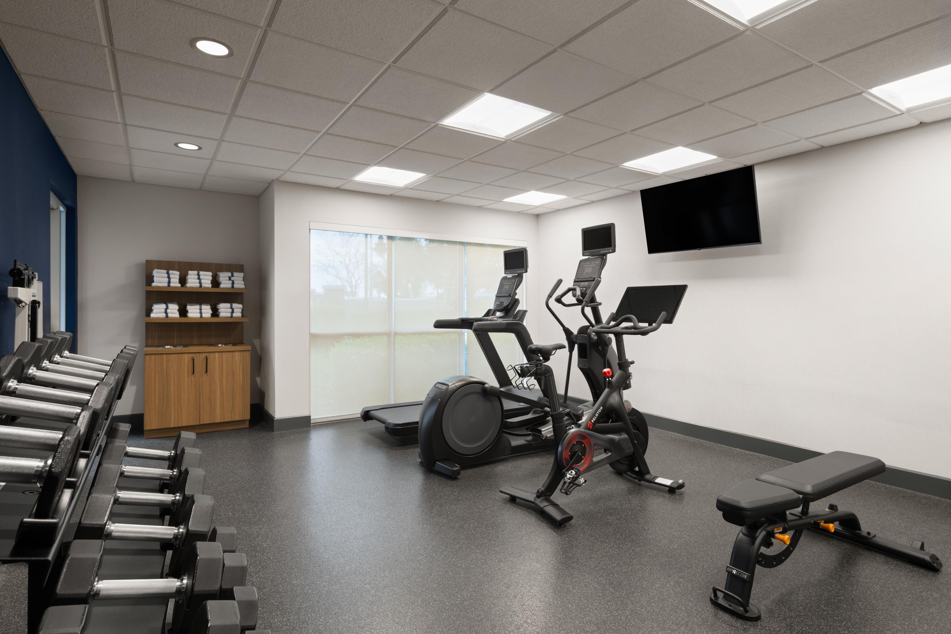 A gym with exercise equipment, a television, and a window.