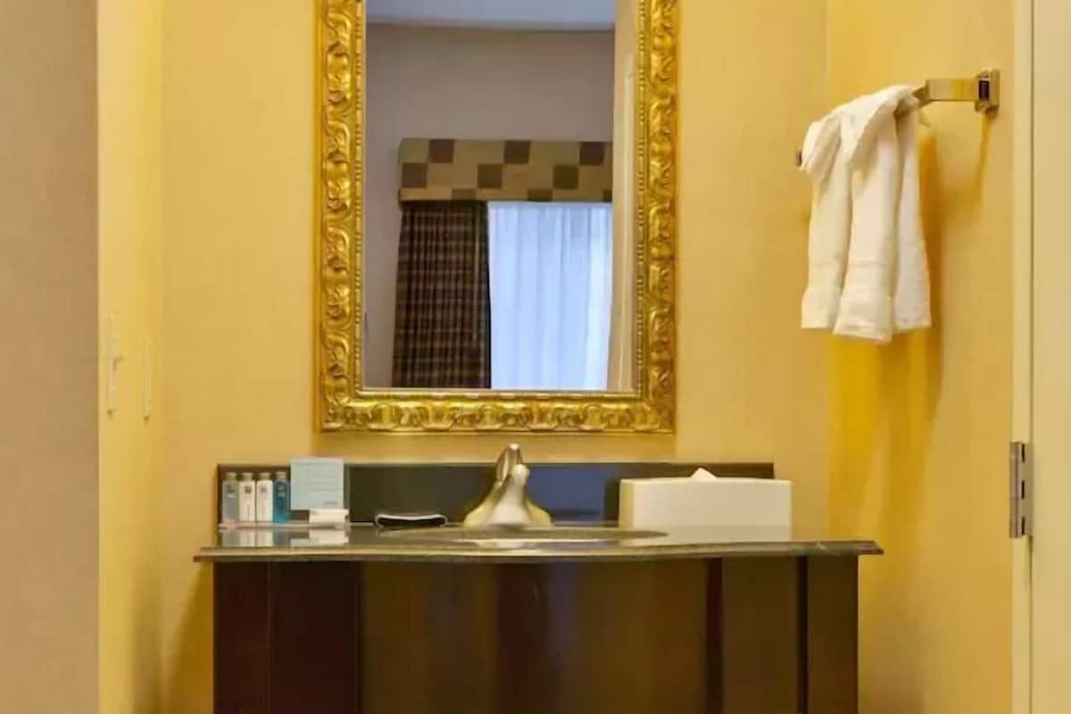 A bathroom with a mirror, sink, and towel rack.