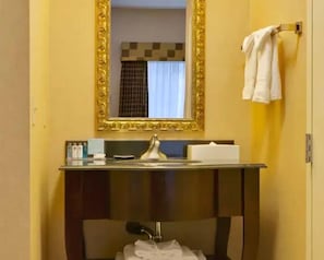 A bathroom with a mirror, sink, and towel rack.