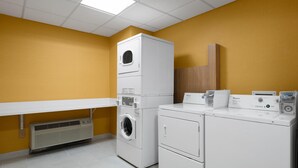 A laundry room with stacked washers and dryers, a vent, and a wooden panel on the wall. - Hampton Inn & Suites Sacramento-Airport-Natomas (Sacramento)