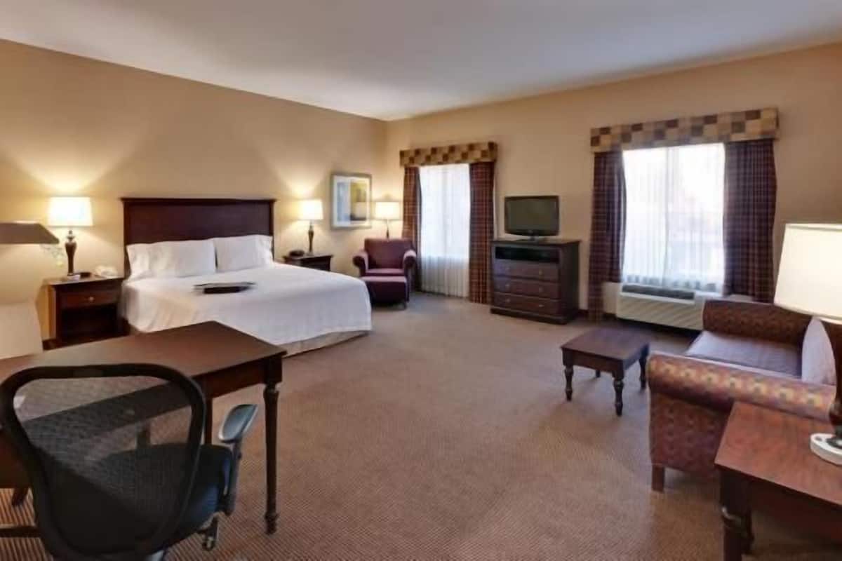 A hotel room with a bed, desk, chair, TV, and a sofa.