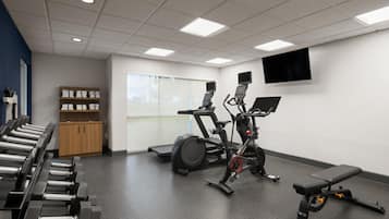 A gym with exercise equipment, a television, and a window.