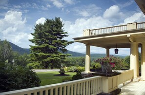 A covered porch with a view of a mountain landscape. - The Manor On Golden Pond (Holderness)