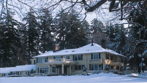 Una casa grande de dos pisos con techo nevado y un porche delantero.
