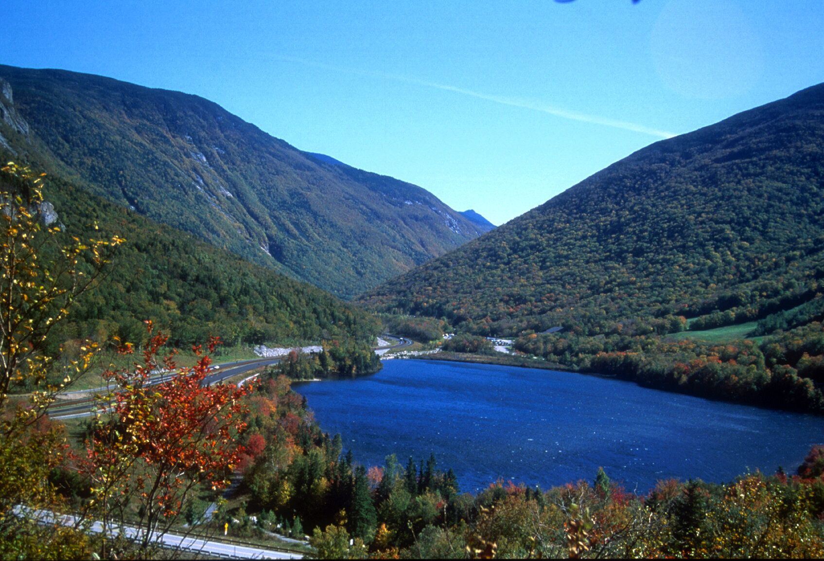 A mountainous landscape with a lake and a road.