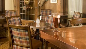 Interior acogedor de restaurante con muebles de madera, una mesa redonda y una jarra de cerveza.
