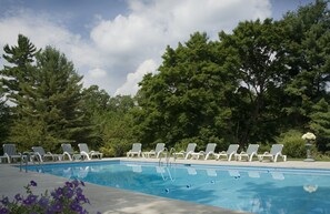 A swimming pool with white lounge chairs and a clear sky. - The Manor On Golden Pond (Holderness)