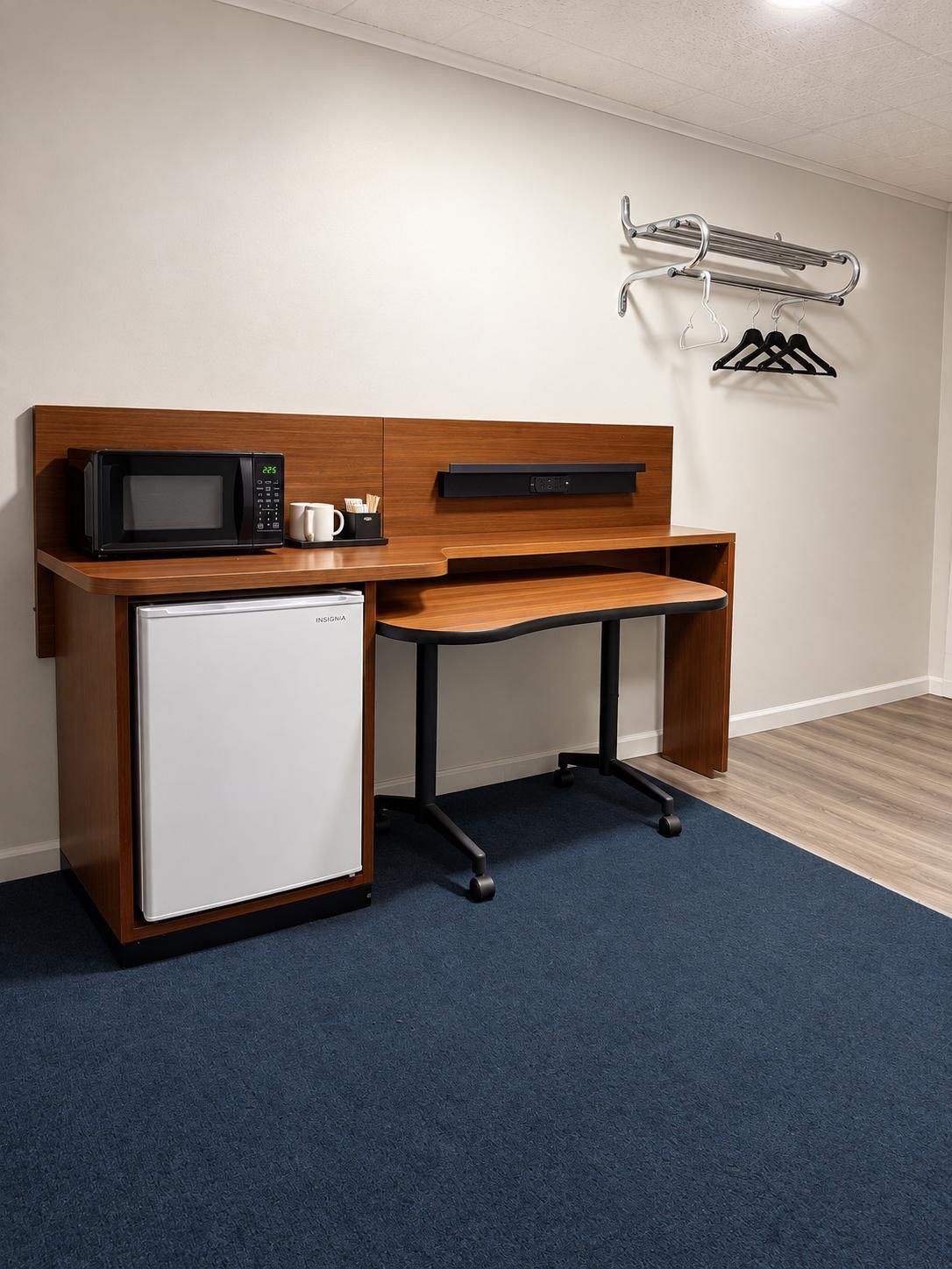 Una kitchenette compacta con microondas, refrigerador y un pequeño lavamanos.