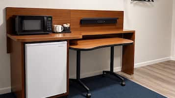 Una kitchenette compacta con microondas, refrigerador y un pequeño lavamanos.