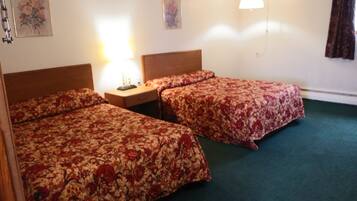 A hotel room with two beds, a nightstand, a lamp, and a hanging light fixture.