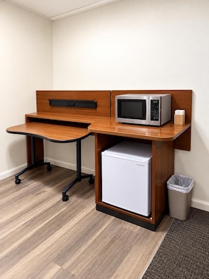 A compact kitchenette with a microwave, refrigerator, and a small trash bin. - Crown Inn & Suites (Wellsville)