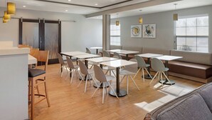 A modern dining area with tables and chairs, a counter, and a sofa.