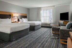 Une chambre d’hôtel avec deux lits, un canapé, une télévision et une petite table.