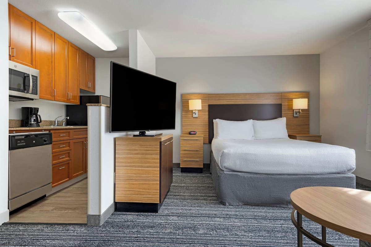 Ein Hotelzimmer mit Bett, Nachttischen, Fernseher, Kaffeemaschine und Mikrowelle.