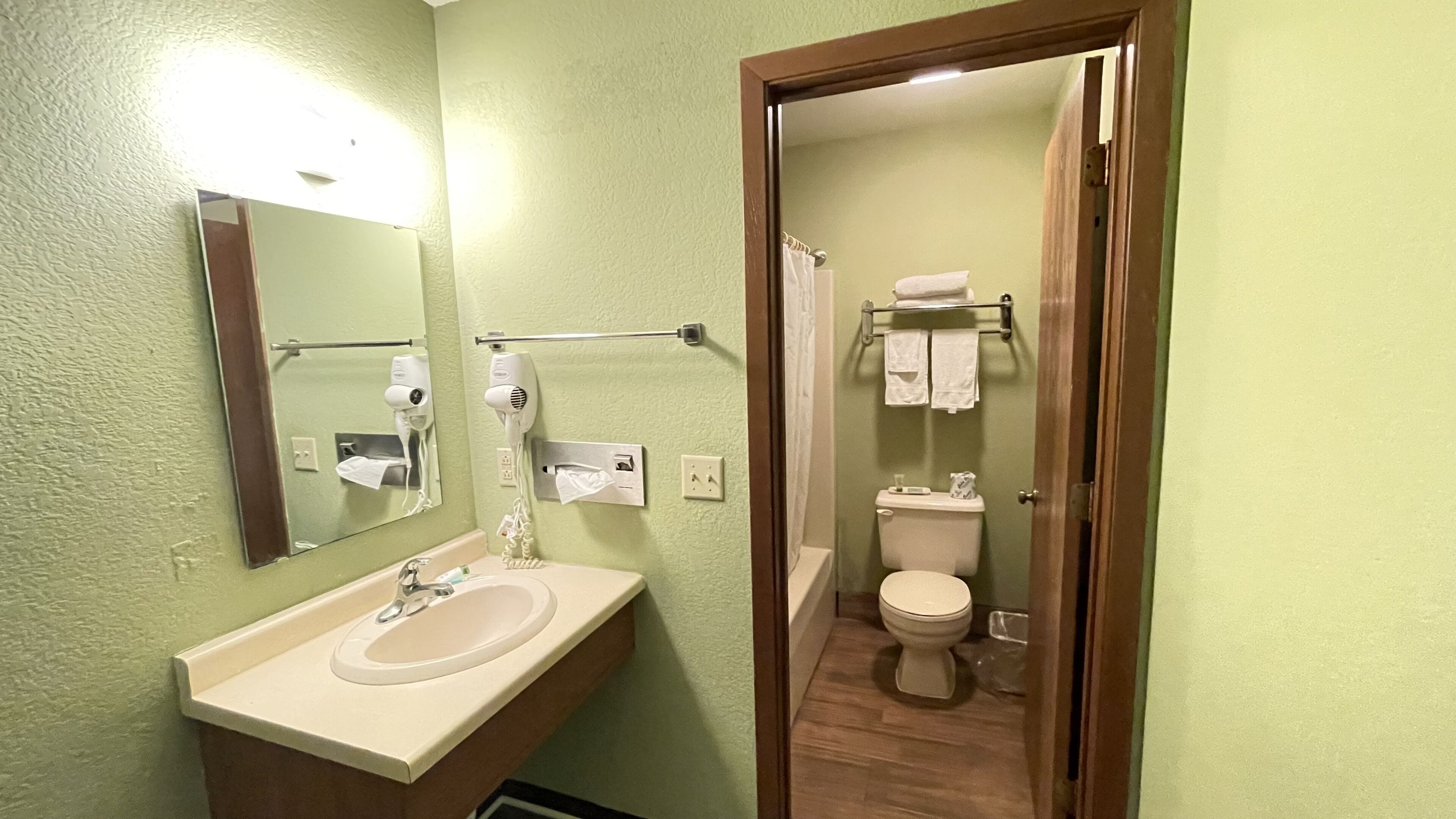 Une salle de bain équipée d’un lavabo, d’un miroir, d’un sèche-cheveux et d’un porte-serviettes.