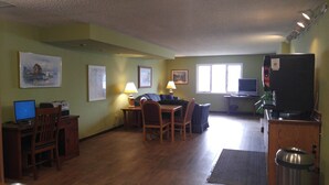 A compact living space with a dining area, a small kitchen, and a seating area with a television. - Harbor Lights Lodge (Kewaunee)