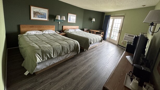 A hotel room with two beds, a desk, a chair, a TV, and a window with curtains. - Harbor Lights Lodge (Kewaunee)