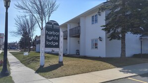 A sign for Harbor Lights Lodge with a white building and a covered walkway. - Harbor Lights Lodge (Kewaunee)