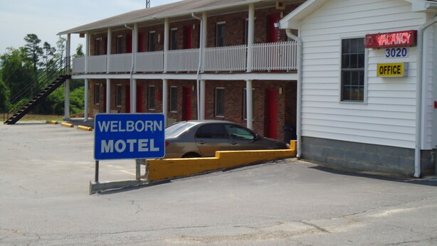 Et motel med en toetages bygning, en synlig receptionsdisk og et skilt, der viser ledige værelser.