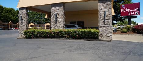 A McMinnville Inn with a stone facade, a covered parking area, and a signboard.