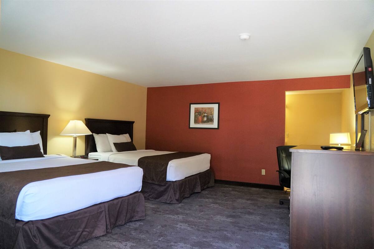 Une chambre d’hôtel avec deux lits, un bureau, une chaise et un téléviseur.