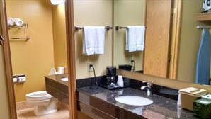 A bathroom with a toilet, sink, and a mirror. There are towels hanging on the wall and a coffee maker on the counter. - McMinnville Inn (McMinnville)
