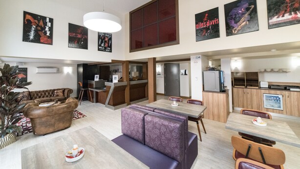 A spacious living area with a sofa, a dining table, and a kitchen area. - Quality Hotel Toulouse Centre (Toulouse)