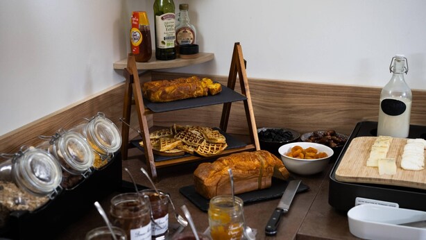 A breakfast buffet with various food items, condiments, and a cutting board with cheese. - Quality Hotel Toulouse Centre (Toulouse)