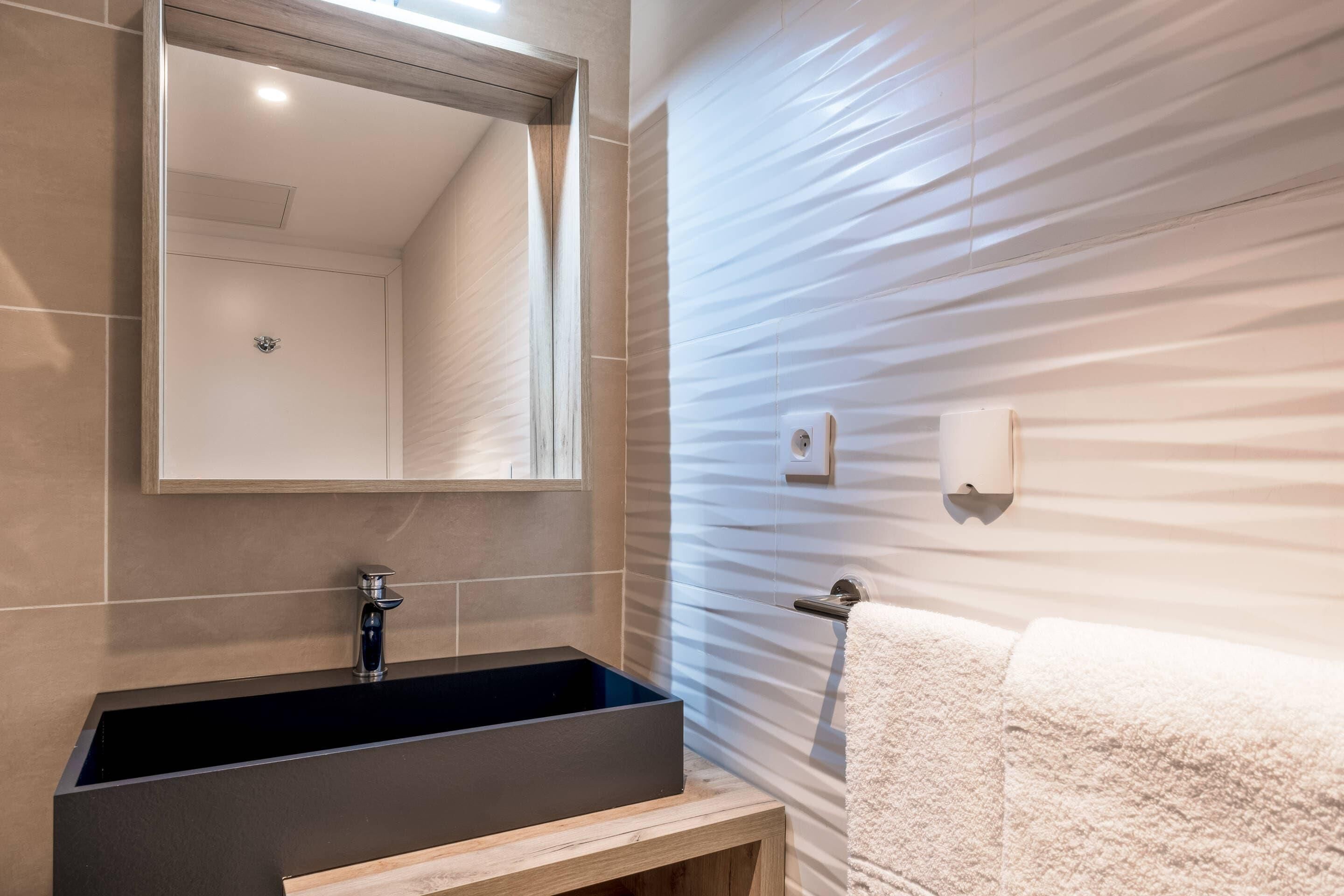 Een moderne badkamer met een rechthoekig wastafel, een spiegel en een handdoekrek.
