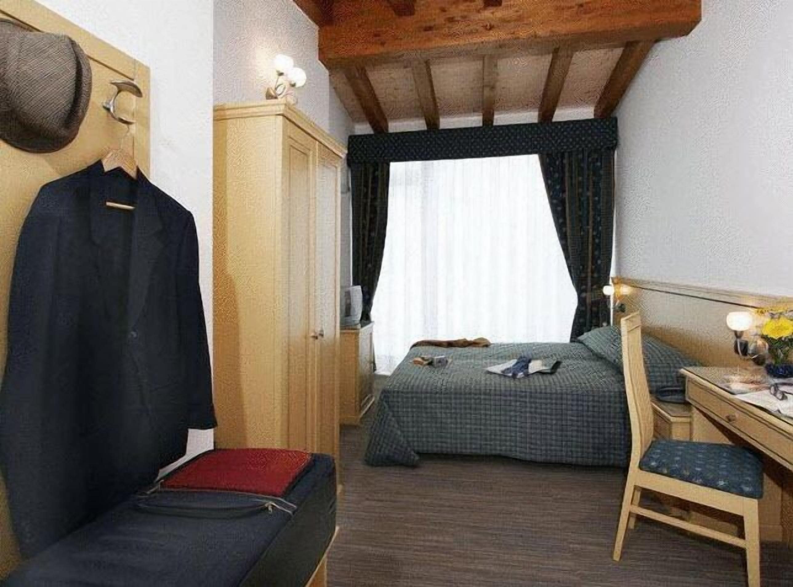 A small, cozy room with a bed, a desk, and a wardrobe.
