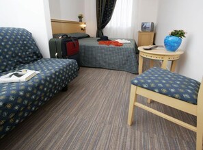 Una habitación de hotel con dos camas, una mesita, una silla y una maleta.