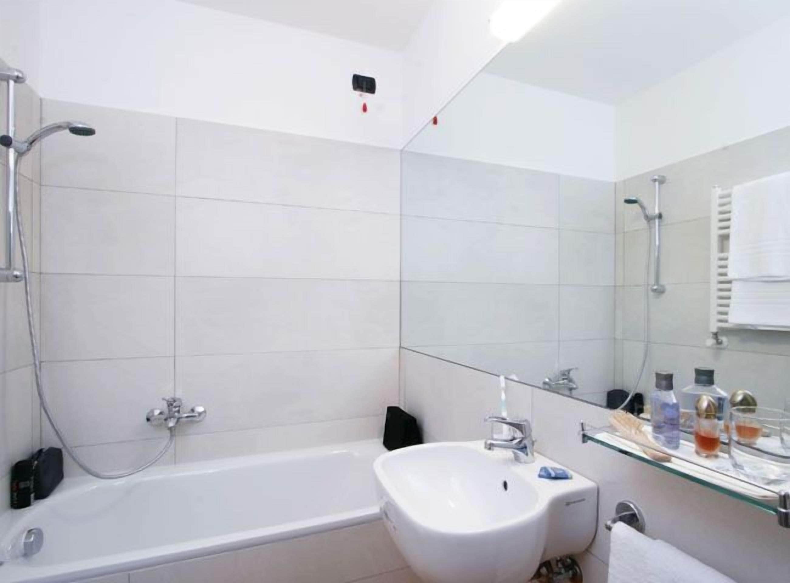 A modern bathroom with a bathtub, a sink, and a glass shower enclosure.