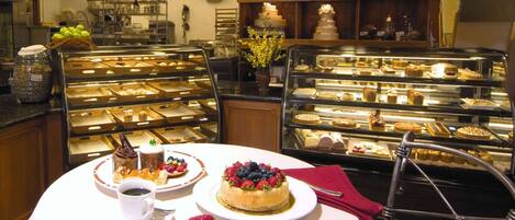 Un mostrador de pastelería con diversos pasteles y postres exhibidos en vitrinas.