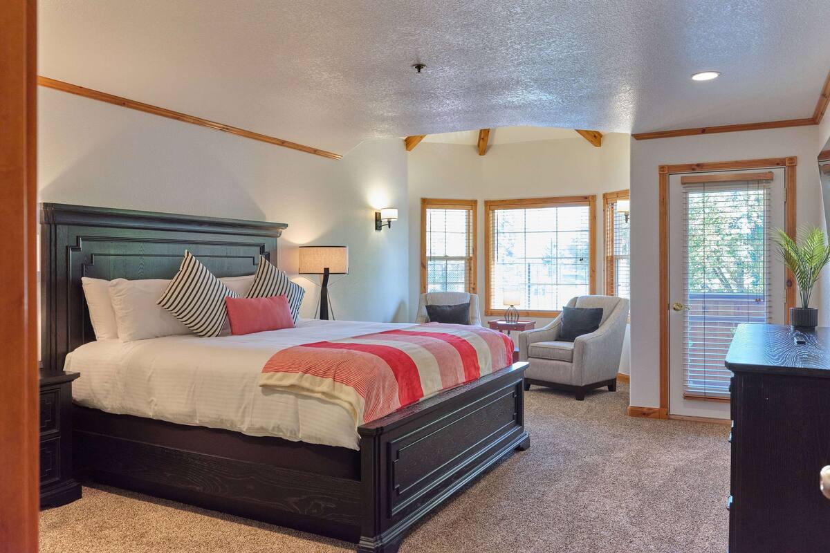 A bedroom with a large bed, a chair, a nightstand, and a dresser.